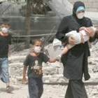 Una mujer libanesa pasa, con sus hijos tapados con máscaras, por delante de los escombros en Beirut