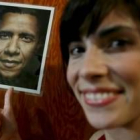 Una simpatizante  de Obama muestra una foto con un gesto de satisfacción sobre el candidato
