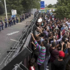 Refugiados sirios ante la valla fronteriza de Hungría.