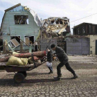 Un hombre empuja una carretilla ante una vivienda destruida por los combates en la ciudad de Debáltsevo , Ucrania.