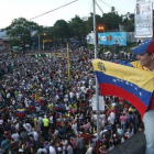 Un simpatizante de la oposición ondea una bandera venezolana ante cientos de personas congregadas para celebrar los resultados electorales en Venezuela.