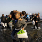 Un refugiado sirio llegado de Turquía carga con un niño en la isla griega de Kos.