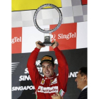 Fernando Alonso levanta su trofeo en el podio, tras lograr el tercer puesto en Singapur, este domingo.