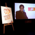 Videoconferencia de Puigdemont, junto a un cartel de Junts per Catalunya.