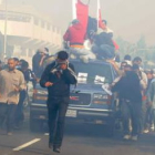 Manifestantes se cubren del gas lacrimógeno mientras escoltan el coche fúnebre de Ali Abdul Mushima.