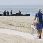 Una pareja se dirige a la playa mientras la Guardia Civil inspecciona el cadáver del niño. QUIQUE GARCÍA