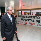 Guisasola pasa, con gesto serio, delante de la pancarta de los trabajadores.