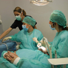 Uno de las pacientes de la Clínica Solidaria del Colegio de Dentistas de León se somete a un tratamiento ante la atenta mirada de dos alumnos. F. OTERO PERANDONES
