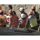 Miembros del cuerpo de bomberos y protección civil trasladan el cuerpo sin vida rescatado de una de las tres personas que habían quedado atrapadas en su vivienda-cueva tras el desprendimiento de un gran talud de tierra.