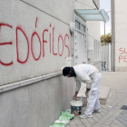 Un pintor repasa con pintura blanca una pintadas con acusaciones de pedofilia y pederastia en una parroquia de Granada. PEPE TORRES