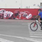 Un ciclista pasa por delante del mural alusivo a la Vuelta a España 2023 situado en la calle Julio Hernández de La Bañeza. RAMIRO