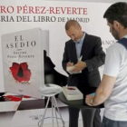 El escritor Arturo Pérez-Reverte firma libros al primer lector de la larguísima cola.