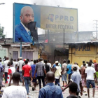 Opositores del presidente Kabila gritan consignas contra el mandatario mientras destruyen un cartel con su imagen, en Kinshasa, capital de la República Democrática del Congo, este lunes.