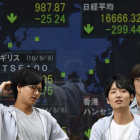 Japoneses en Tokio ante un monitor con la evolución de la bolsa.