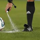 Un árbitro usando spray para marcar el lugar desde donde lanzar la falta