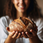 Una mujer sostiene entre sus manos una hogaza de pan. NUTRITIENDA