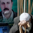 El padre del dirigente de Hamás asesinado Mahmud al Mabhuh se sienta ante un póster con la imagen de