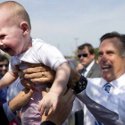 Mitt Romney devuelve a un bebé a su madre, el jueves en Springfield (Virginia).
