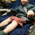Un niño viaja en un atubús con el cinturón de seguridad puesto.