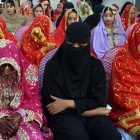 Mujeres paquistaníes vestidas con trajes de novia tradicionales participan en una boda en masa.