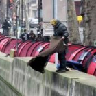 Un hombre sacude una manta a un canal de París, donde acampa gente sin hogar