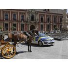 Un coche de caballos y una patrulla policial junto a una de las tribunas, en la Plaza de la Virgen de los Reyes, que estaban preparadas para la visita del presidente de EEUU Barack Obama a Sevilla, que finalmente ha sido cancelada