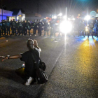 Un joven trata de detener que la policía cargue contra los manifestantes en Ferguson.