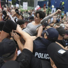 Un grupo de personas intentan romper la barrera formada por la policia durante una protesta en Polonia