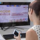 Una empleada del Ayuntamiento de Sevilla ante la web abierta para votar sobre la duración de la Feria de Abril.