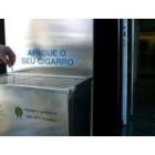 Un fumador apaga su cigarrillo en unos ceniceros instalados por la Xunta