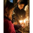 Unas niñas encienden velas en la iglesia de la Natividad de Belén