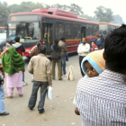 Varias personas esperan la llegada de autobuses en una barriada de Delhi.