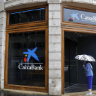 Una mujer observa la sede de Caixa Bank en la plaza del Ayuntamiento de Valencia. MANUEL BRUQUE