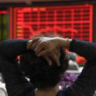 Una mujer comprueba la evolución de la bolsa de Shangái.