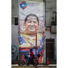 Un hombre espera en una motocicleta frente a publicidad en apoyo del presidente venezolano, Hugo Chávez, en las afueras del hospital militar Dr. Carlos Arvelo.