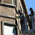 Dos bomberos de Ponferrada trabajan en las labores de retirada de cascotes, ayer en la avenida Valdé