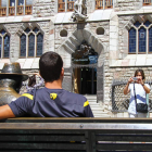 Una pareja de turistas haciéndose una foto junto a la escultura de Gaudí frente a Botines.