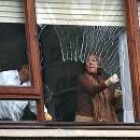Una pareja quita los cristales de la ventana que rompió la explosión