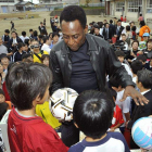 Pelé entrega un balón firmado a unos niños de una escuela de Fujigaoka, en Japón.