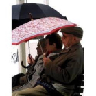 Un grupo de pensionistas se protegen del sol con un paraguas