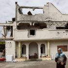 Una mujer permanece junto a su casa, parcialmente destruida por los bombardeos en Sirte.