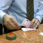 Un trabajador de un banco contando un fajo de billetes de diez euros
