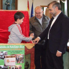 La ‘mano inocente’ entrega al alcalde la papeleta premiada en el sorteo.