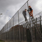 Dos operarios trabajan en la instalación de malla antitrepa entre Melilla y Marruecos.