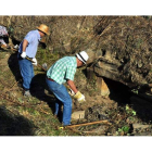 Voluntarios de Promonumenta limpiando y recolocando la cámara sepulcral de Santa Colomba de Somoza.  DAVID GUSTAVO LÓPEZ
