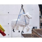 La estatua ecuestre de Franco, tapada y colgando de una grúa durante su traslado al almacén.