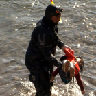 Un guardia saca del agua el cuerpo de una niña en Grecia.