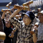Unos ancianos japoneses realizan ejercicio con unas mancuernas de madera en Tokio