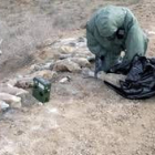 Un soldado danés examina los proyectiles de mortero encontrados al borde de una carretera