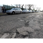 La principal calle que atraviesa el barrio, con cientos de coches a diario, se encuentra en el estado que muestra la imagen. ANA F. BARREDO